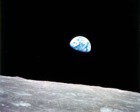 Earthrise — Apollo 8. This view of the rising Earth greeted the Apollo 8 astronauts as they came from behind the Moon after the lunar orbit insertion burn. Earth is about five degrees above the horizon in the photo. The unnamed surface features in the foreground are near the eastern limb of the Moon as viewed from Earth. The lunar horizon is approximately 780 kilometers from the spacecraft. Width of the photographed area at the horizon is about 175 kilometers. On the Earth 240,000 miles away, the sunset terminator bisects Africa.